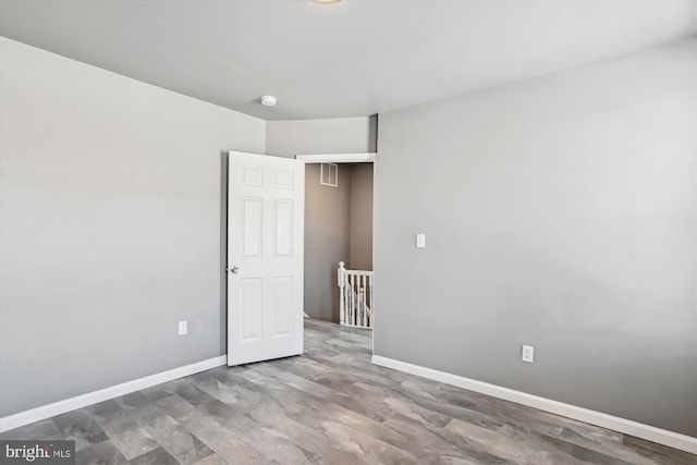 spare room with baseboards and wood finished floors