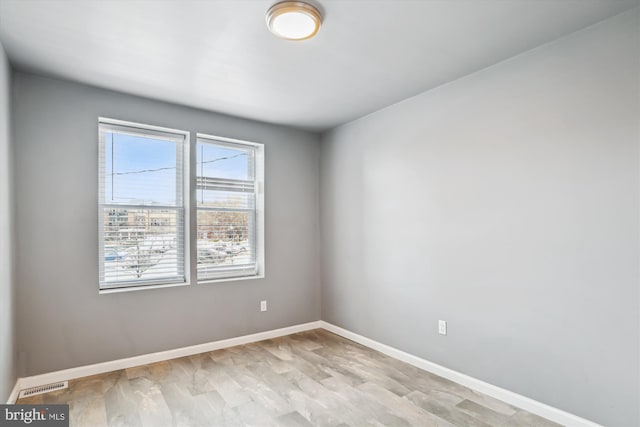 spare room with baseboards, light wood finished floors, and visible vents