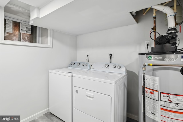 washroom featuring water heater, baseboards, laundry area, and washer and clothes dryer