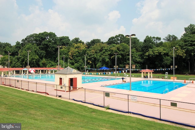 community pool with fence and a yard