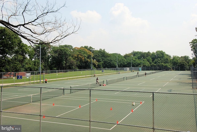 view of tennis court featuring fence and community basketball court