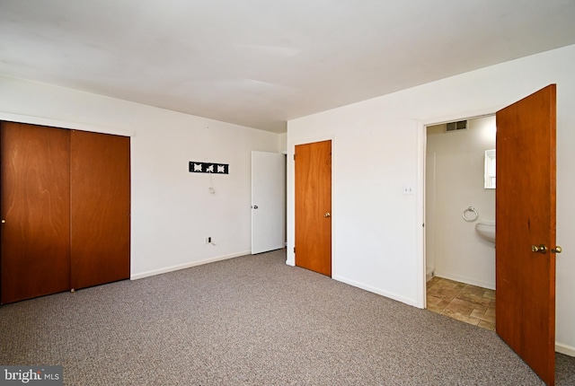 unfurnished bedroom with connected bathroom, carpet floors, two closets, baseboards, and visible vents