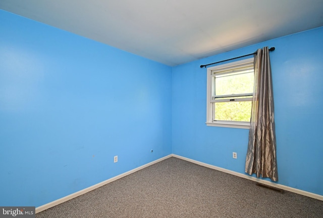 carpeted empty room featuring visible vents and baseboards