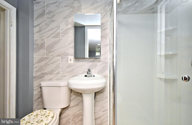 bathroom featuring tile walls, a shower stall, and toilet