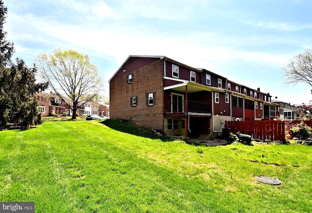 back of house with brick siding, central air condition unit, fence, and a yard