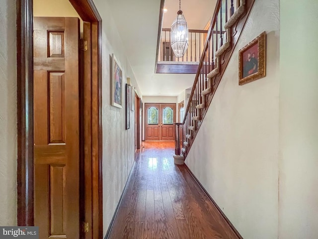 corridor with baseboards, dark wood-style floors, and stairway