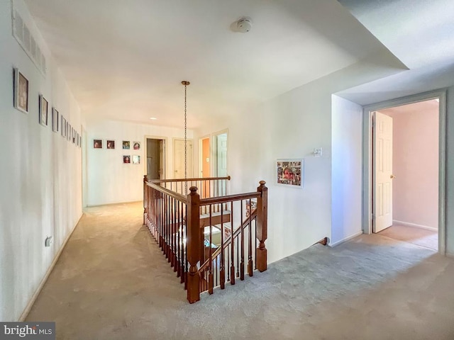 corridor with visible vents, carpet, and an upstairs landing