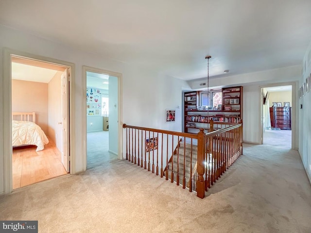 hallway with carpet flooring and an upstairs landing