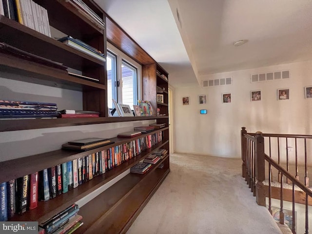 corridor featuring light colored carpet, visible vents, and an upstairs landing