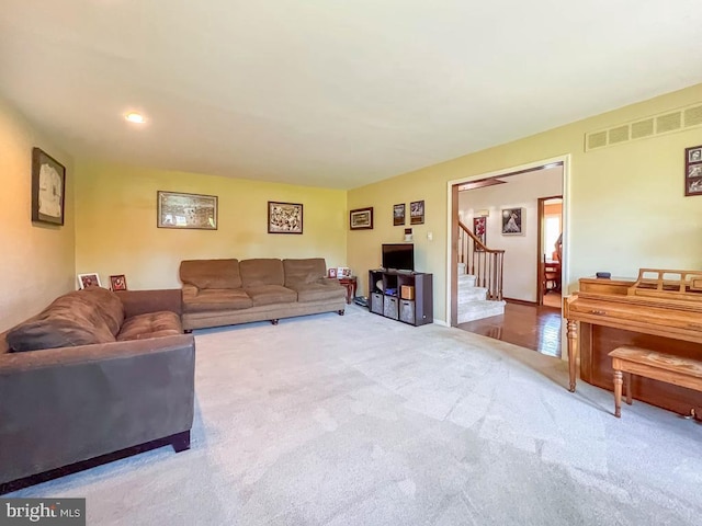 carpeted living room featuring stairway and visible vents
