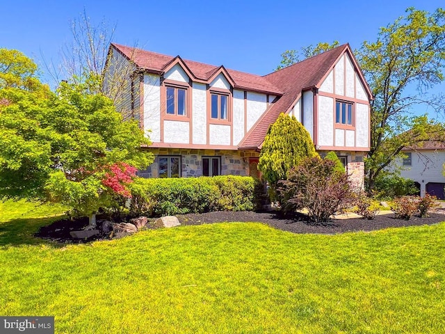 tudor-style house featuring a front yard and stone siding