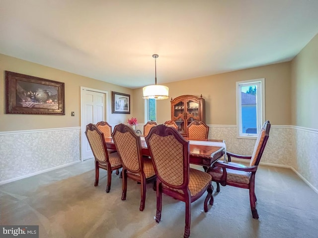 carpeted dining room with wallpapered walls and wainscoting