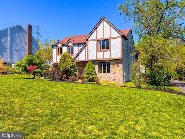 english style home featuring a front yard and stone siding