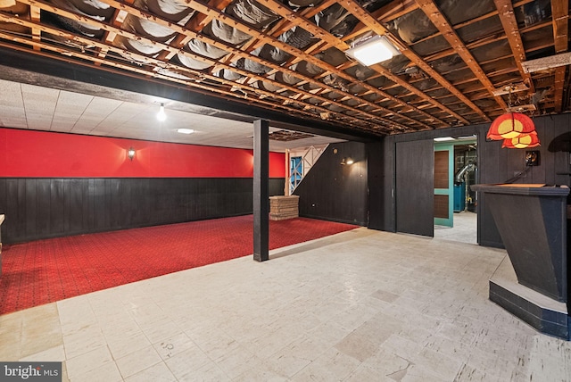 finished basement with wooden walls, carpet floors, and a wainscoted wall