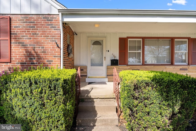 entrance to property featuring brick siding, board and batten siding, and a porch
