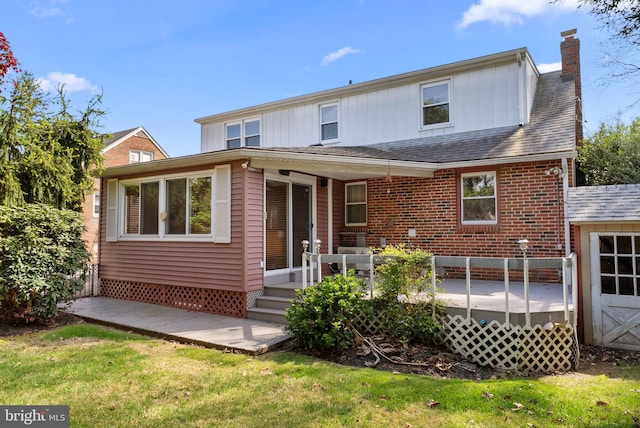 rear view of property with a yard, a deck, board and batten siding, and a chimney