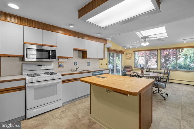 kitchen featuring wooden counters, lofted ceiling with skylight, a center island, a sink, and stainless steel appliances