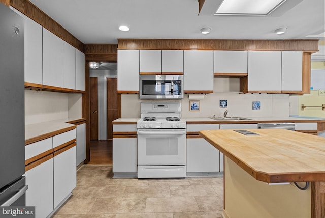 kitchen featuring stainless steel appliances, recessed lighting, white cabinetry, and butcher block counters