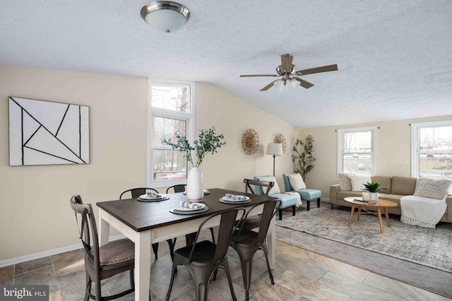 dining area featuring stone tile floors, a ceiling fan, a textured ceiling, and lofted ceiling