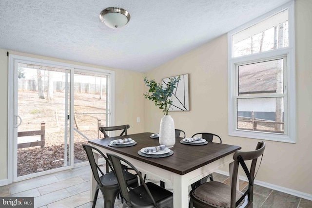 dining room with light tile patterned floors, a textured ceiling, and baseboards