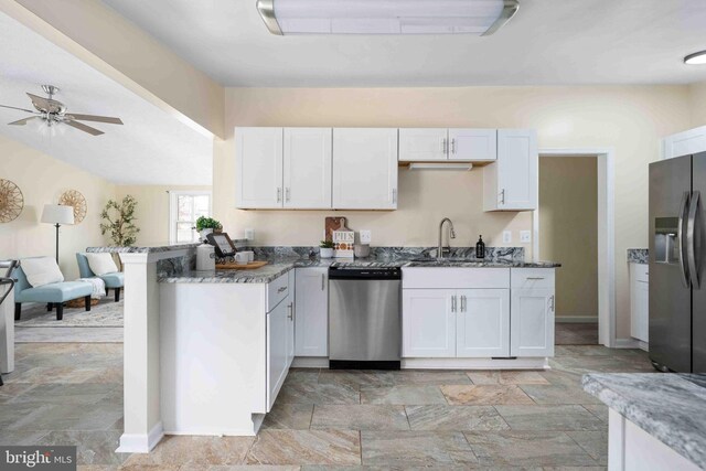 kitchen with stone finish floor, ceiling fan, a sink, stone countertops, and stainless steel appliances