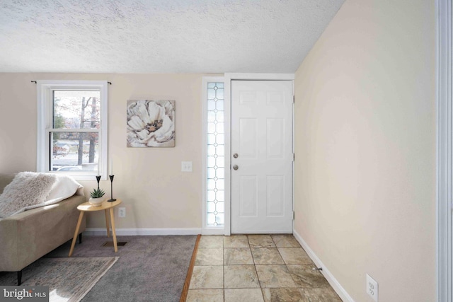foyer with a textured ceiling, baseboards, and visible vents