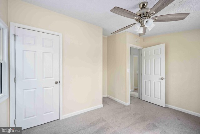 unfurnished bedroom featuring baseboards, carpet flooring, a textured ceiling, and ceiling fan
