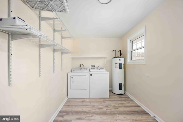 washroom featuring laundry area, washing machine and dryer, wood finished floors, baseboards, and water heater