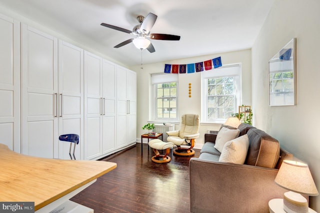 living area with dark wood-type flooring, baseboards, ceiling fan, and radiator heating unit