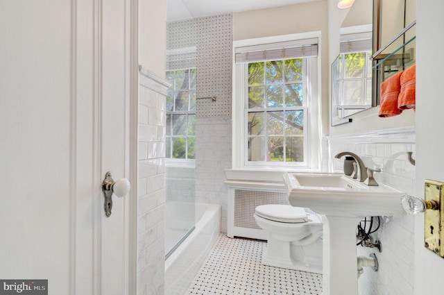 full bathroom with toilet, tile walls, a healthy amount of sunlight, and radiator heating unit
