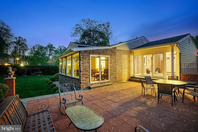 8610 Westmeath Ct, Springfield, VA 22152 - back of property at dusk featuring a lawn, a patio area, brick siding, fence, and outdoor dining space