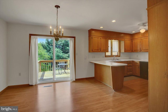 kitchen featuring light countertops, a peninsula, baseboards, and light wood-type flooring
