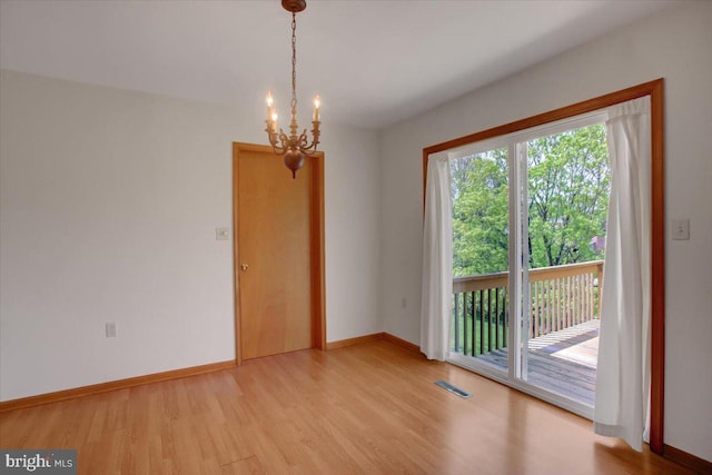 unfurnished room with baseboards, visible vents, light wood-type flooring, and a chandelier