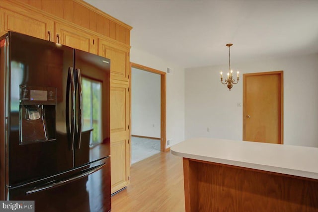 kitchen with a notable chandelier, light countertops, black refrigerator with ice dispenser, decorative light fixtures, and light wood-type flooring