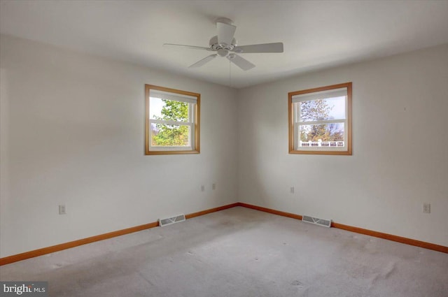 carpeted empty room with baseboards, visible vents, and ceiling fan