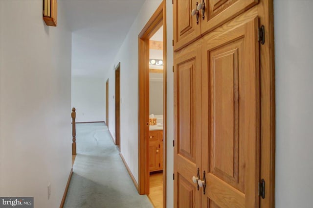 corridor featuring baseboards, an upstairs landing, and light carpet