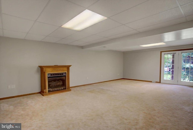 unfurnished living room with carpet flooring, baseboards, and a paneled ceiling