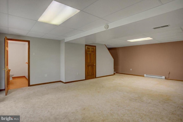 finished basement with carpet flooring, baseboard heating, a paneled ceiling, baseboards, and visible vents