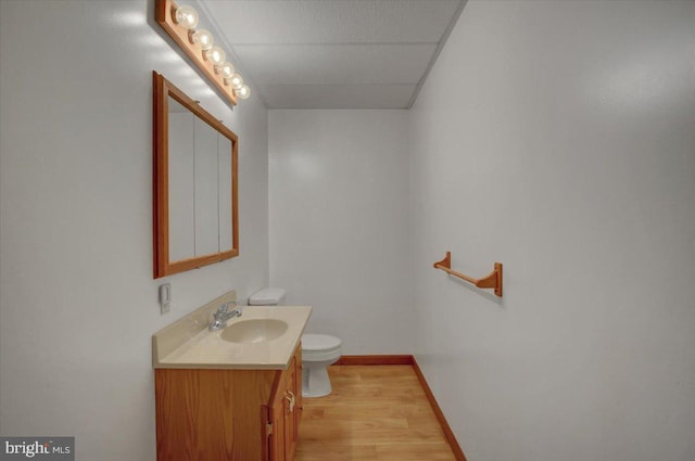 bathroom with toilet, baseboards, wood finished floors, and vanity