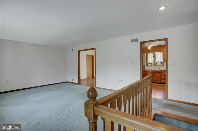 empty room featuring baseboards, light carpet, and visible vents