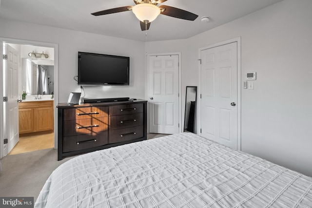 bedroom with a closet, light carpet, ceiling fan, a sink, and ensuite bath