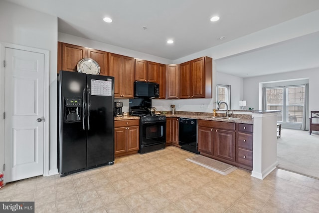 kitchen featuring brown cabinetry, a sink, a peninsula, and black appliances