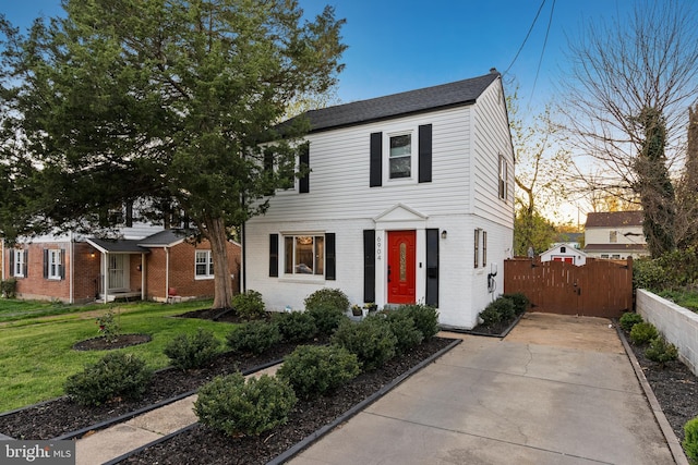 view of front of house featuring fence, concrete driveway, a front yard, and brick siding