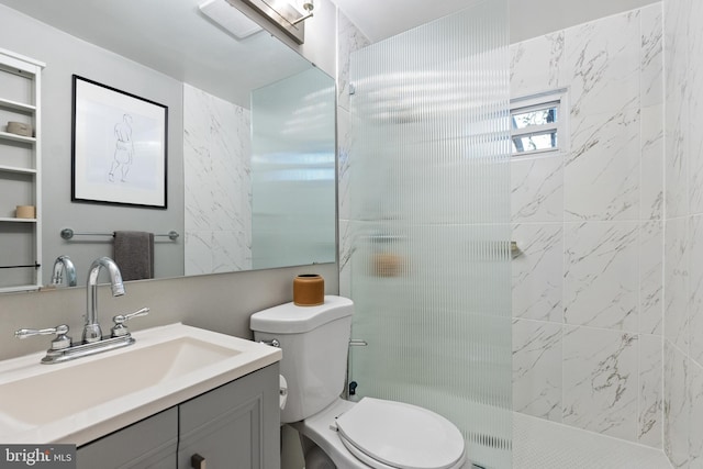 bathroom with vanity, a tile shower, and toilet