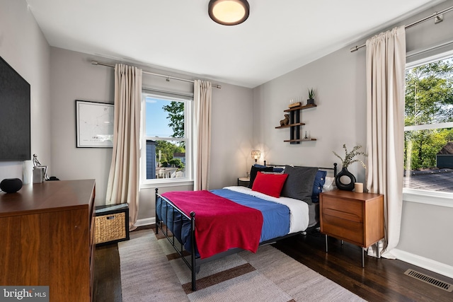 bedroom with visible vents, baseboards, wood finished floors, and multiple windows