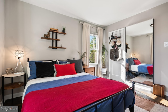 bedroom with baseboards, connected bathroom, and wood finished floors