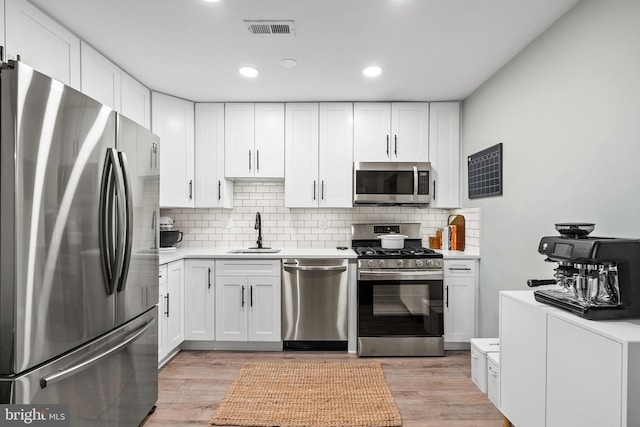kitchen featuring backsplash, a sink, light countertops, white cabinets, and stainless steel appliances