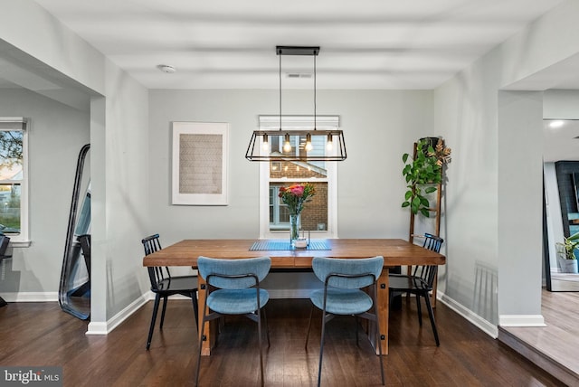 dining room featuring a notable chandelier, baseboards, visible vents, and dark wood-type flooring