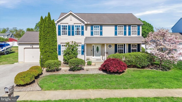 view of front of home featuring a porch, a garage, driveway, and a front yard