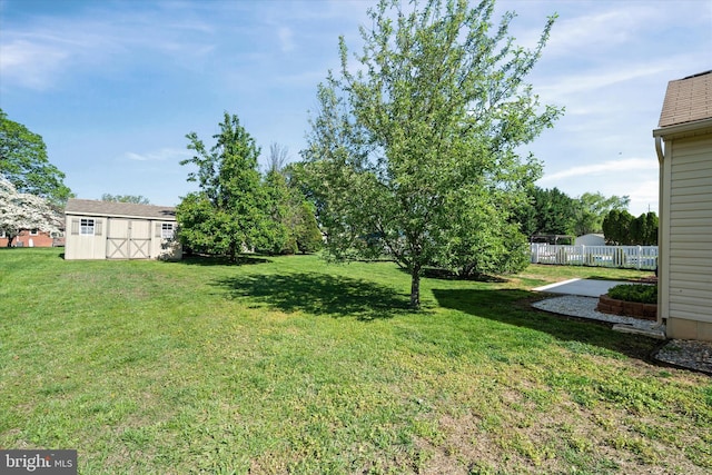 view of yard featuring a storage unit, an outdoor structure, and fence